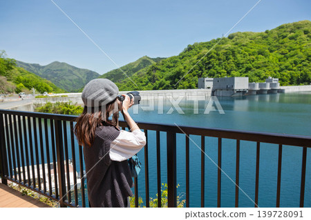 A woman photographs the Yamba Dam in early summer. A woman photographs the Yamba Dam in early summer. 139728091