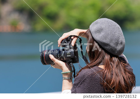 A woman photographs a lake in early summer at Lake Yamba-Agatsuma. A woman photographs a lake in early summer at Lake Yamba-Agatsuma. 139728132