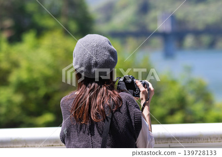 A woman photographs a lake in early summer at Lake Yamba-Agatsuma. A woman photographs a lake in early summer at Lake Yamba-Agatsuma. 139728133