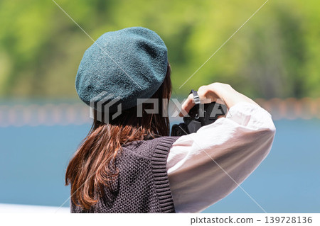 A woman photographs a lake in early summer at Lake Yamba-Agatsuma. A woman photographs a lake in early summer at Lake Yamba-Agatsuma. 139728136