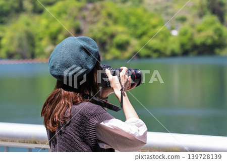 A woman photographs a lake in early summer at Lake Yamba-Agatsuma. A woman photographs a lake in early summer at Lake Yamba-Agatsuma. 139728139