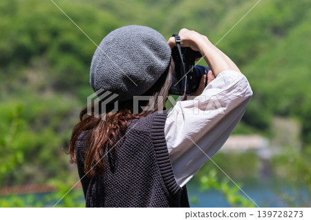 A woman photographs the early summer scenery at Lake Yamba-Agatsuma. A woman photographs the early summer scenery at Lake Yamba-Agatsuma. 139728273