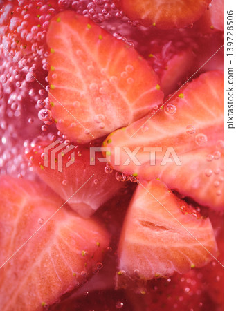 Fresh strawberries floating in sparkling water with bubbles and vibrant colors in a glass container Fresh strawberries floating in sparkling water with bubbles and vibrant colors in a glass container 139728506