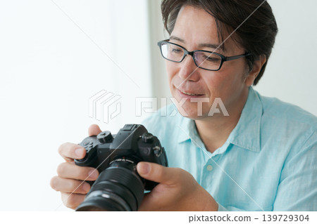 A man smiling with a camera in his hand. 139729304