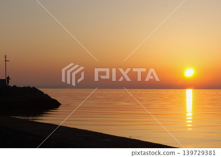 The beautiful sunrise over Aioi Fishing Port in Kagawa Prefecture, and the silhouettes of people fishing on the breakwater. The beautiful sunrise over Aioi Fishing Port in Kagawa Prefecture, and the silhouettes of people fishing on the breakwater. 139729381