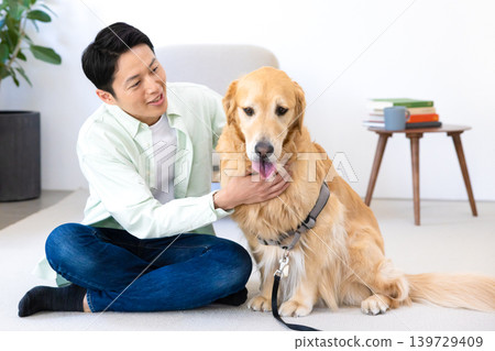 Pet: Golden Retriever - A man relaxing with his dog in the living room. Pet: Golden Retriever - A man relaxing with his dog in the living room. 139729409
