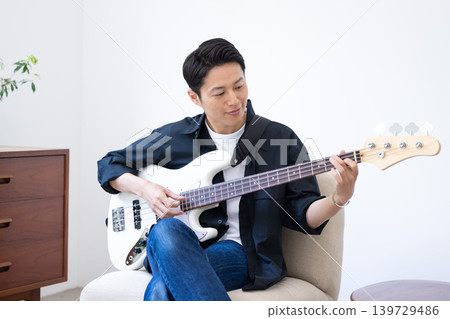 A man whose hobby is playing musical instruments, specifically the bass guitar. A man whose hobby is playing musical instruments, specifically the bass guitar. 139729486