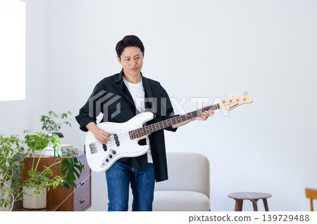 A man whose hobby is playing musical instruments, specifically the bass guitar. A man whose hobby is playing musical instruments, specifically the bass guitar. 139729488