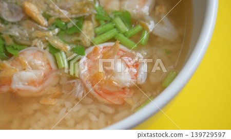 rice soup with shrimp in white bowl on yellow background rice soup with shrimp in white bowl on yellow background 139729597