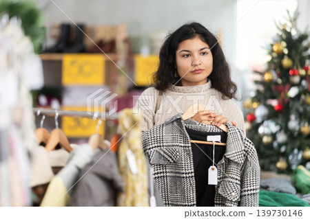 Woman chooses coat or jacket for the winter period in fashionable clothing store Woman chooses coat or jacket for the winter period in fashionable clothing store 139730146