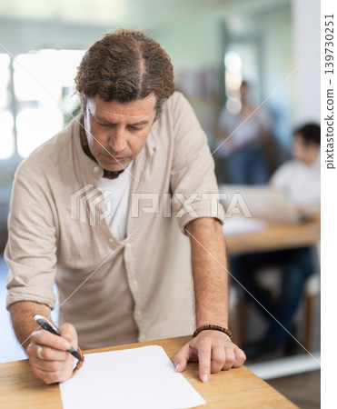 Portrait of manager reading and signing documents in modern office Portrait of manager reading and signing documents in modern office 139730251