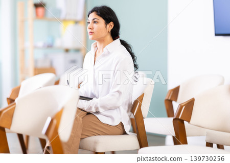 During lecture meeting, female pupil listen to teacher and write down summary in tablet 139730256