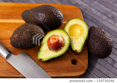 Whole and halved avocados on wooden cutting board Whole and halved avocados on wooden cutting board 139730298