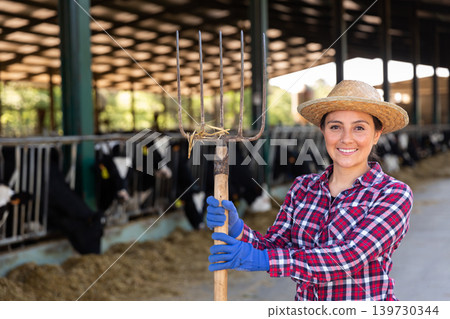 Successful young female cow breeder standing in cowshed Successful young female cow breeder standing in cowshed 139730344