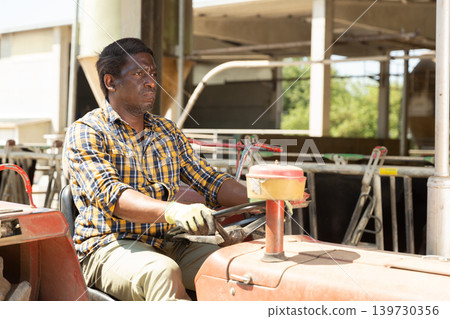 Afro american farmer sitting in a tractor Afro american farmer sitting in a tractor 139730356