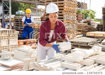 Attentive asian woman is laying bricks Attentive asian woman is laying bricks 139730373