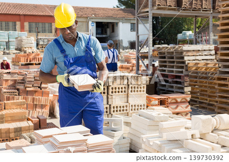 Focused african american man lays tiles in a warehouse Focused african american man lays tiles in a warehouse 139730392