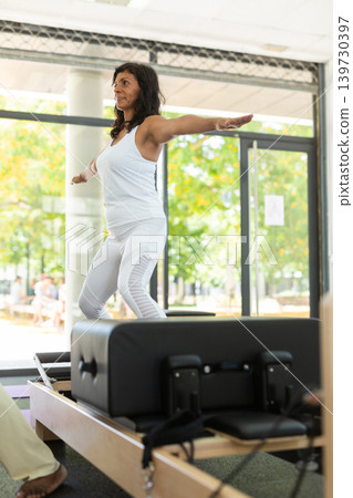 Young woman performing set of pilates exercises on reformer Young woman performing set of pilates exercises on reformer 139730397