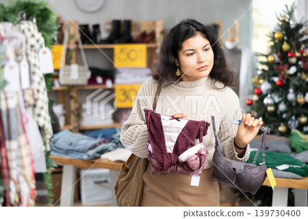 Latina chooses a bra against the background of a Christmas tree in a store Latina chooses a bra against the background of a Christmas tree in a store 139730400