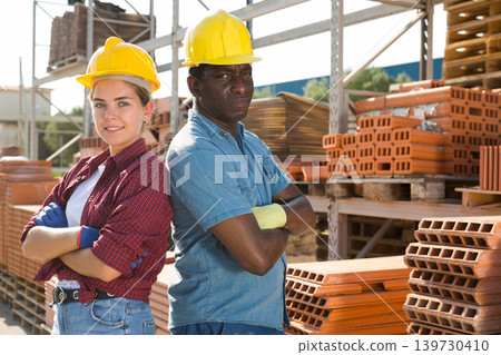 Workers in hardhats standing in construction material storage 139730410