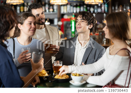 Young friends meeting at table in bar, discussion and drinking beer Young friends meeting at table in bar, discussion and drinking beer 139730443