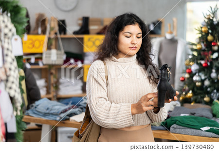 Latina chooses heeled boots on the background of a Christmas tree 139730480
