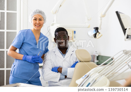 Positive confident dentist with female assistant in dental office Positive confident dentist with female assistant in dental office 139730514