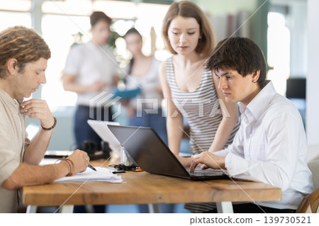 Employees working with laptops and paper documents in office Employees working with laptops and paper documents in office 139730521