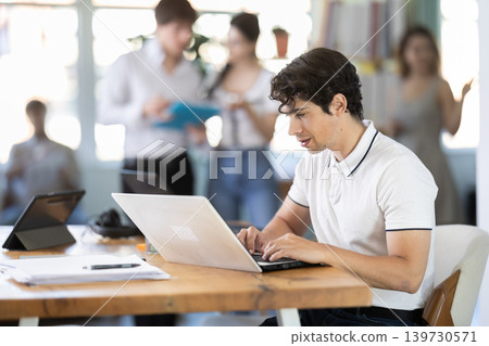 Young man working on laptop in modern office Young man working on laptop in modern office 139730571