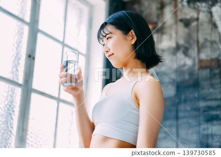 一位年輕女子正在喝礦泉水補充水分。 一位年輕女子正在喝礦泉水補充水分。 139730585