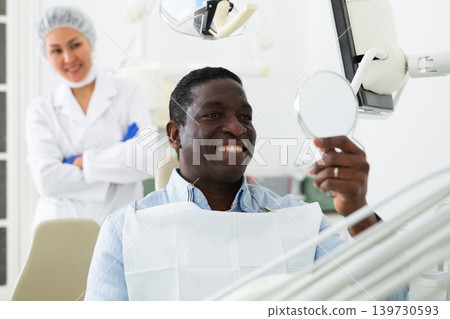 African american patient checks cured teeth with mirror African american patient checks cured teeth with mirror 139730593