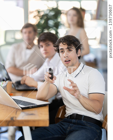 Group of colleagues watching presentation in office Group of colleagues watching presentation in office 139730607