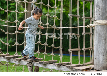 preschool child girl walking on a wooden balancing bridge at outdoor playground preschool child girl walking on a wooden balancing bridge at outdoor playground 139730609