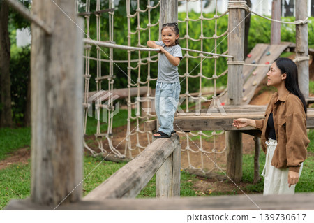 preschool child girl walking on a wooden balancing bridge with her mother at outdoor playground preschool child girl walking on a wooden balancing bridge with her mother at outdoor playground 139730617