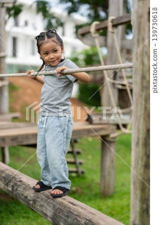 preschool child girl walking on a wooden balancing bridge at outdoor playground preschool child girl walking on a wooden balancing bridge at outdoor playground 139730618