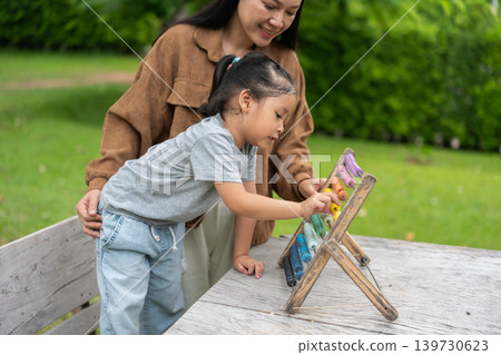 preschool child girl learning and playing colorful wooden abacus with mother 139730623