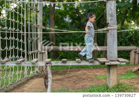 preschool child girl walking on a wooden balancing bridge at outdoor playground preschool child girl walking on a wooden balancing bridge at outdoor playground 139730627