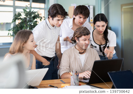 Colleagues looking at one laptop together in office Colleagues looking at one laptop together in office 139730642