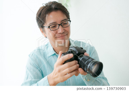 A man smiling with a camera in his hand. 139730903