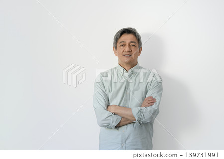 A man in his 60s, arms crossed, smiles and looks directly at the camera. 139731991
