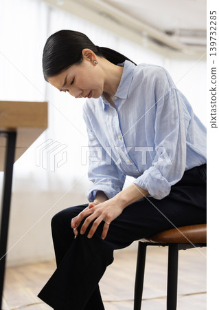 一位日本女子將手放在膝蓋上，露出痛苦的表情。 139732285