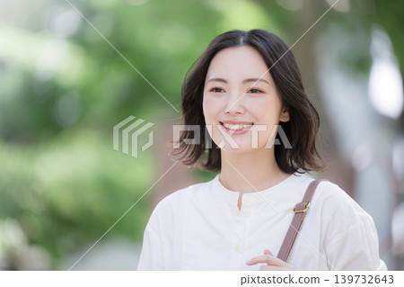 A close-up image of a smiling woman walking through a lush green town, showcasing a natural lifestyle, perfect for commuting or a refreshing outing. A close-up image of a smiling woman walking through a lush green town, showcasing a natural lifestyle, perfect for commuting or a refreshing outing. 139732643