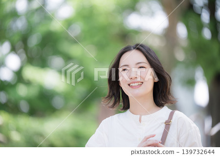 A close-up image of a smiling woman walking through a lush green town, showcasing a natural lifestyle, perfect for commuting or a refreshing outing. A close-up image of a smiling woman walking through a lush green town, showcasing a natural lifestyle, perfect for commuting or a refreshing outing. 139732644