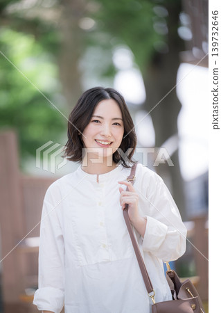 一位微笑的女子漫步在綠樹成蔭的小鎮中,展現出自然的生活方式;非常適合通勤或休閒郊遊,她直視鏡頭。 一位微笑的女子漫步在綠樹成蔭的小鎮中,展現出自然的生活方式;非常適合通勤或休閒郊遊,她直視鏡頭。 139732646