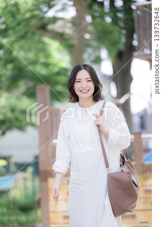 一位微笑的女子漫步在綠樹成蔭的小鎮中,展現出自然的生活方式;非常適合通勤或休閒郊遊,她直視鏡頭。 一位微笑的女子漫步在綠樹成蔭的小鎮中,展現出自然的生活方式;非常適合通勤或休閒郊遊,她直視鏡頭。 139732648