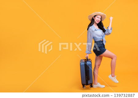Happy Asian woman traveler standing and holding suitcase isolated on yellow background, Tourist girl having cheerful holiday trip concept, Full body composition. Happy Asian woman traveler standing and holding suitcase isolated on yellow background, Tourist girl having cheerful holiday trip concept, Full body composition. 139732887