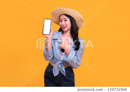 Happy Asian woman woman tourist holding a blank phone isolated on yellow background. Happy Asian woman woman tourist holding a blank phone isolated on yellow background. 139732908