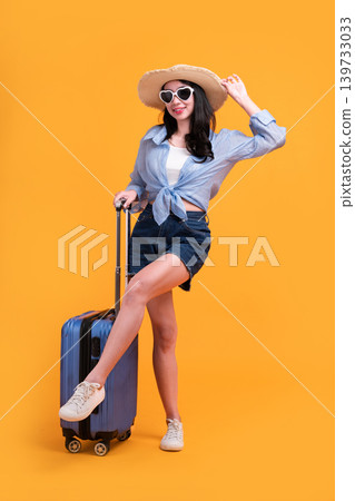 Happy Asian woman traveler standing and holding suitcase isolated on yellow background, Tourist girl having cheerful holiday trip concept, Full body composition. Happy Asian woman traveler standing and holding suitcase isolated on yellow background, Tourist girl having cheerful holiday trip concept, Full body composition. 139733033