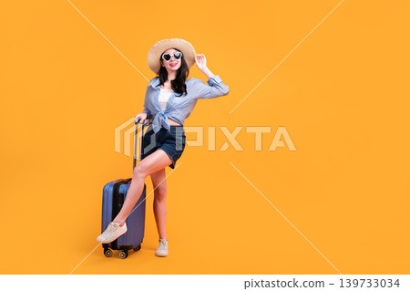 Happy Asian woman traveler standing and holding suitcase isolated on yellow background, Tourist girl having cheerful holiday trip concept, Full body composition. Happy Asian woman traveler standing and holding suitcase isolated on yellow background, Tourist girl having cheerful holiday trip concept, Full body composition. 139733034