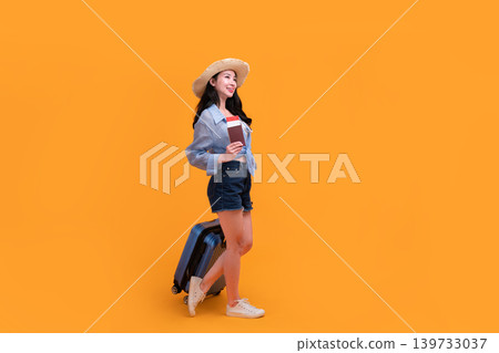 Happy Asian woman traveler standing and holding suitcase isolated on yellow background, Tourist girl having cheerful holiday trip concept, Full body composition. Happy Asian woman traveler standing and holding suitcase isolated on yellow background, Tourist girl having cheerful holiday trip concept, Full body composition. 139733037